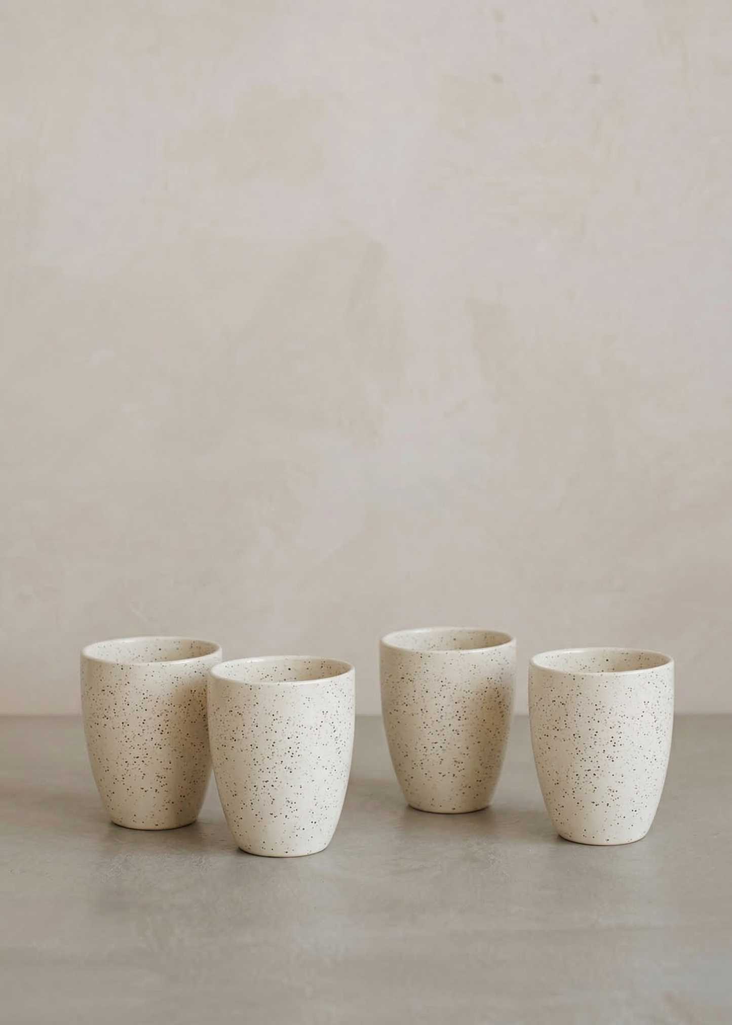 Four ceramic cups of varying sizes on a neutral background