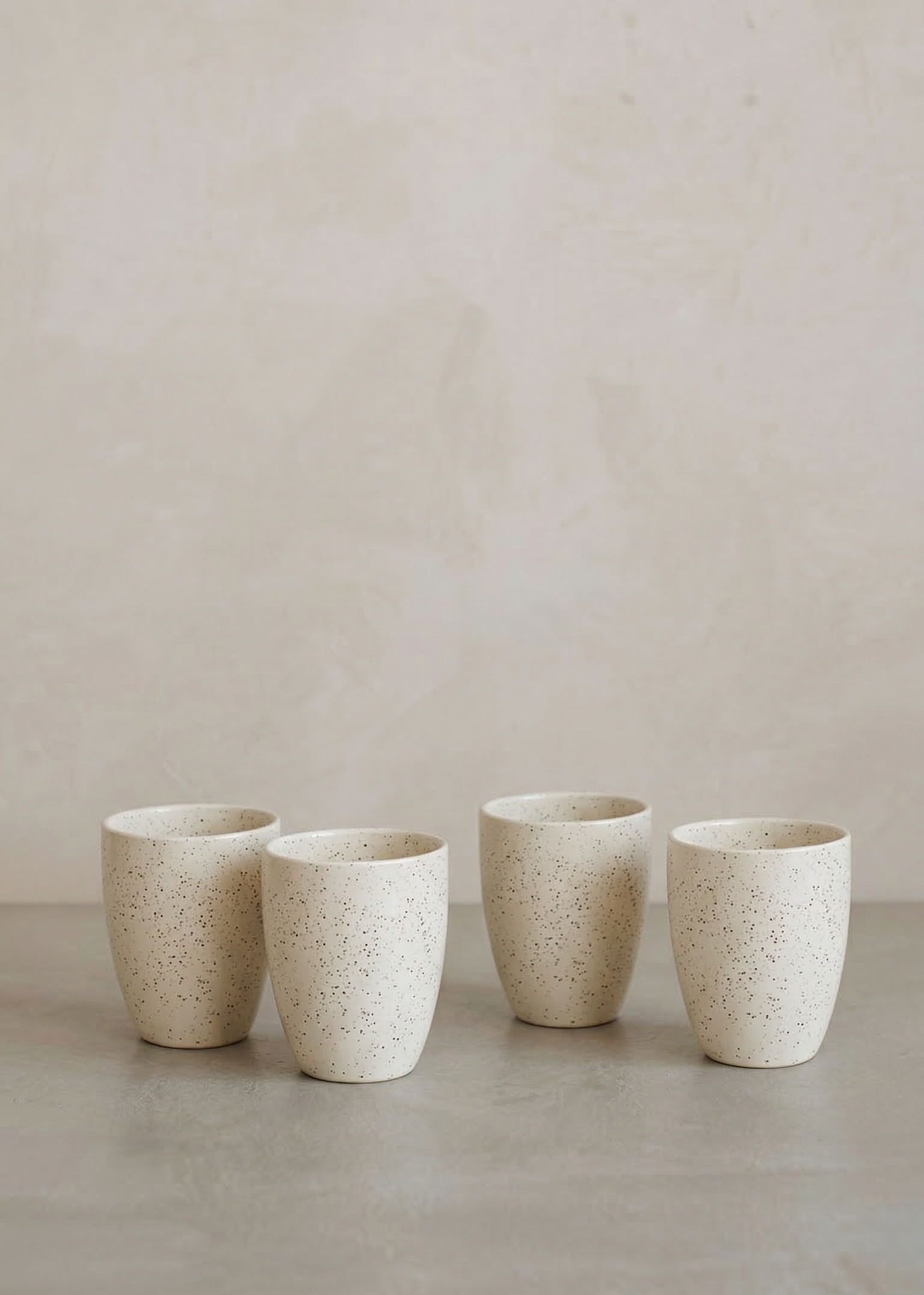 Four ceramic cups of varying sizes on a neutral background