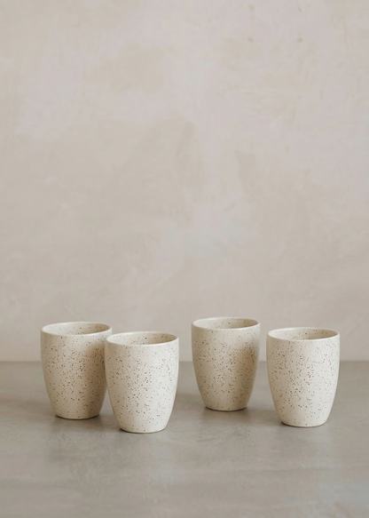 Four ceramic cups of varying sizes on a neutral background