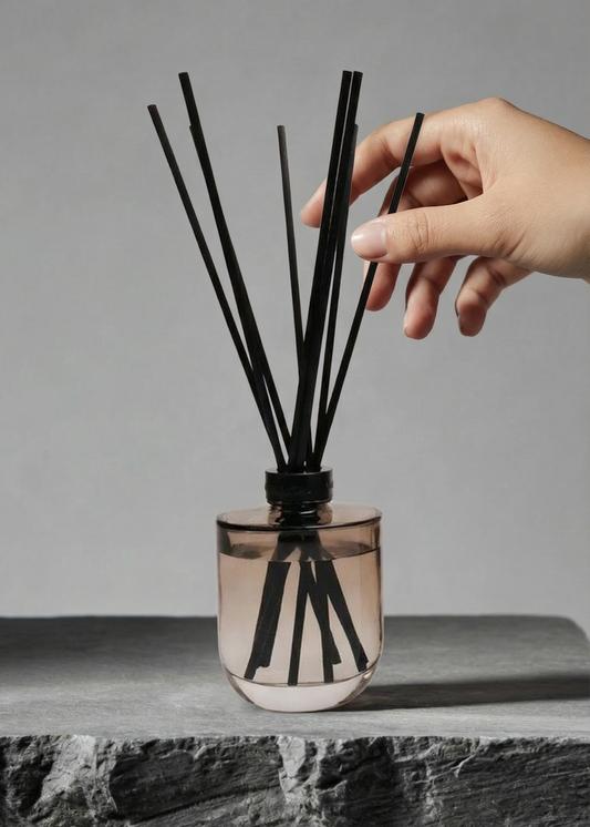 Hand interacting with a diffuser bottle on a gray surface