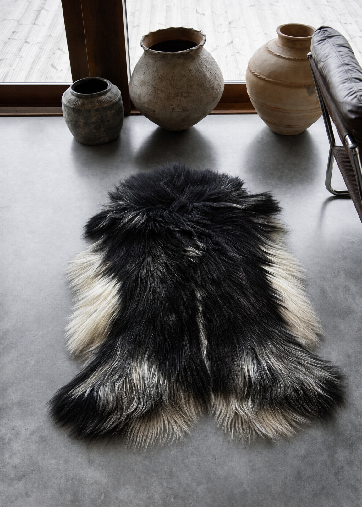 Black and white fur rug on a concrete floor with decorative vases in the background.