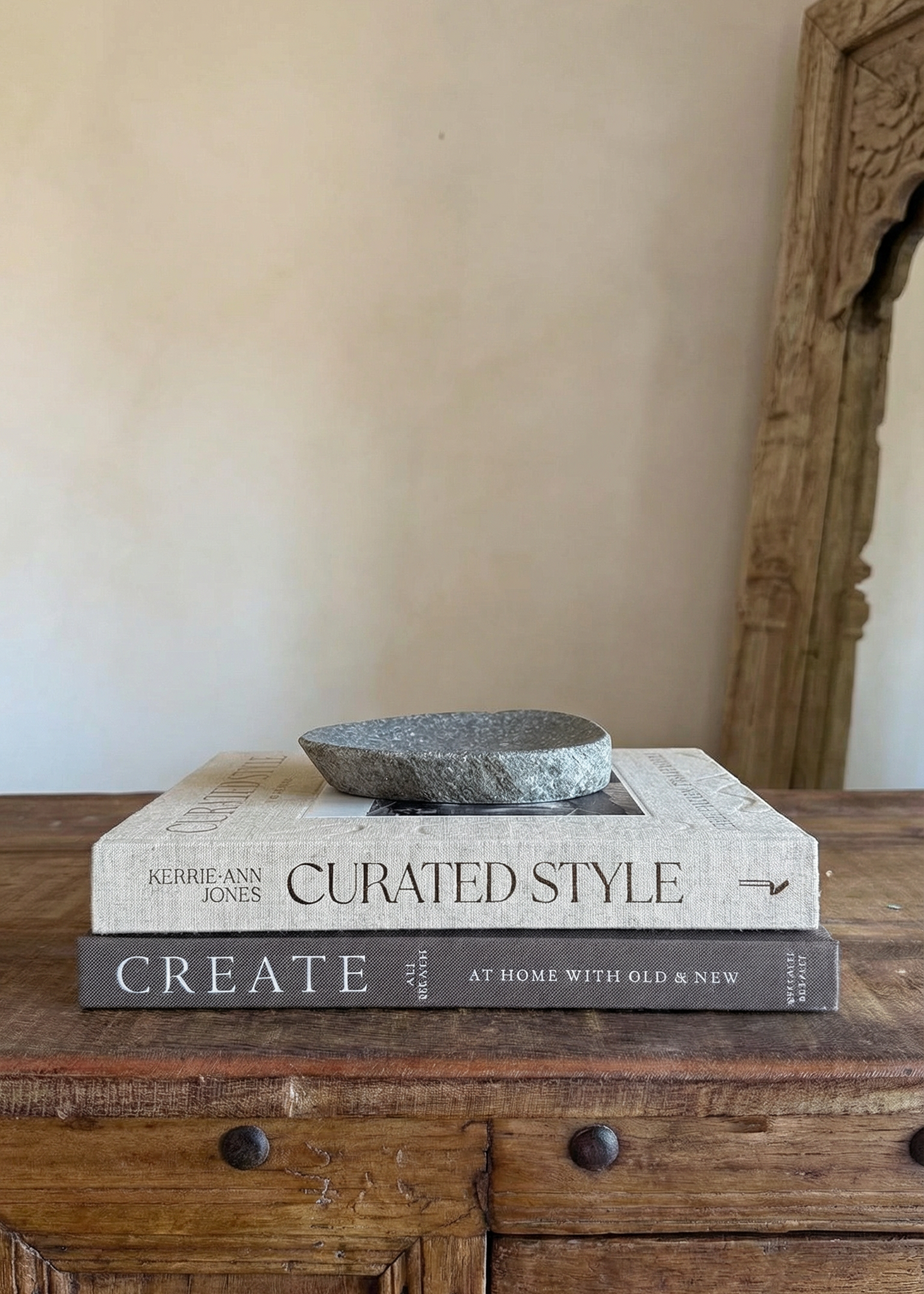 Stack of books titled 'Curated Style' on a wooden surface with a neutral wall background