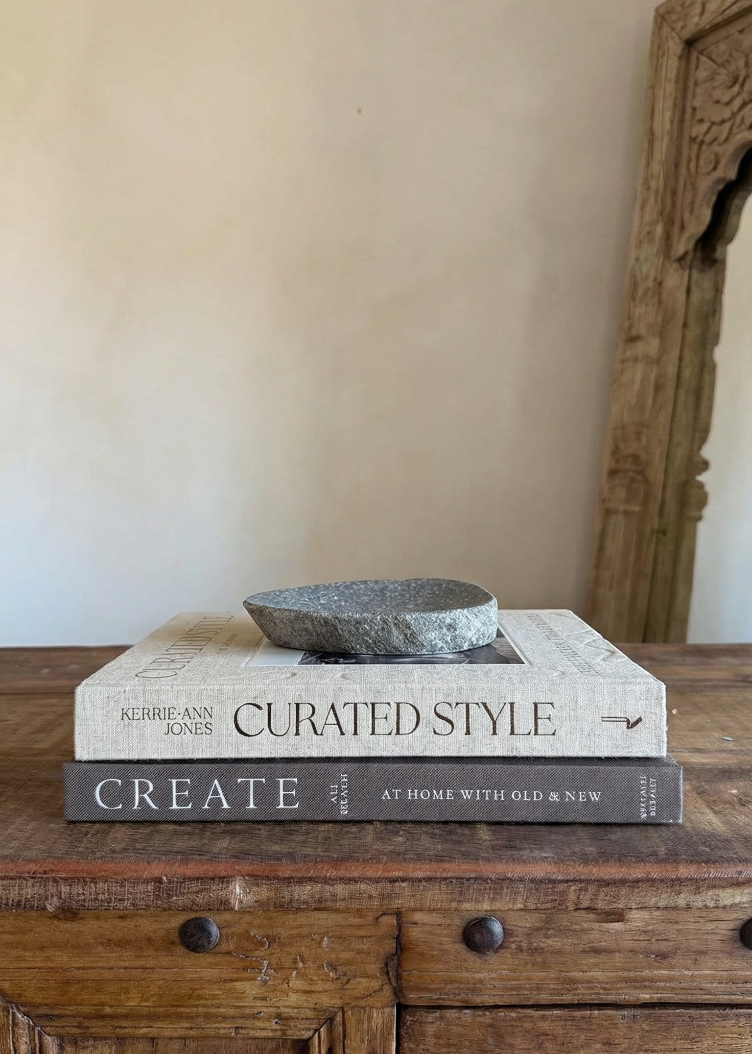 Stack of books titled 'Curated Style' on a wooden surface with a neutral wall background