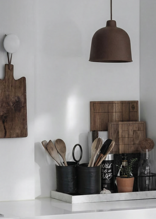 Modern kitchen with white cabinets, wooden cutting boards, and pendant light.
