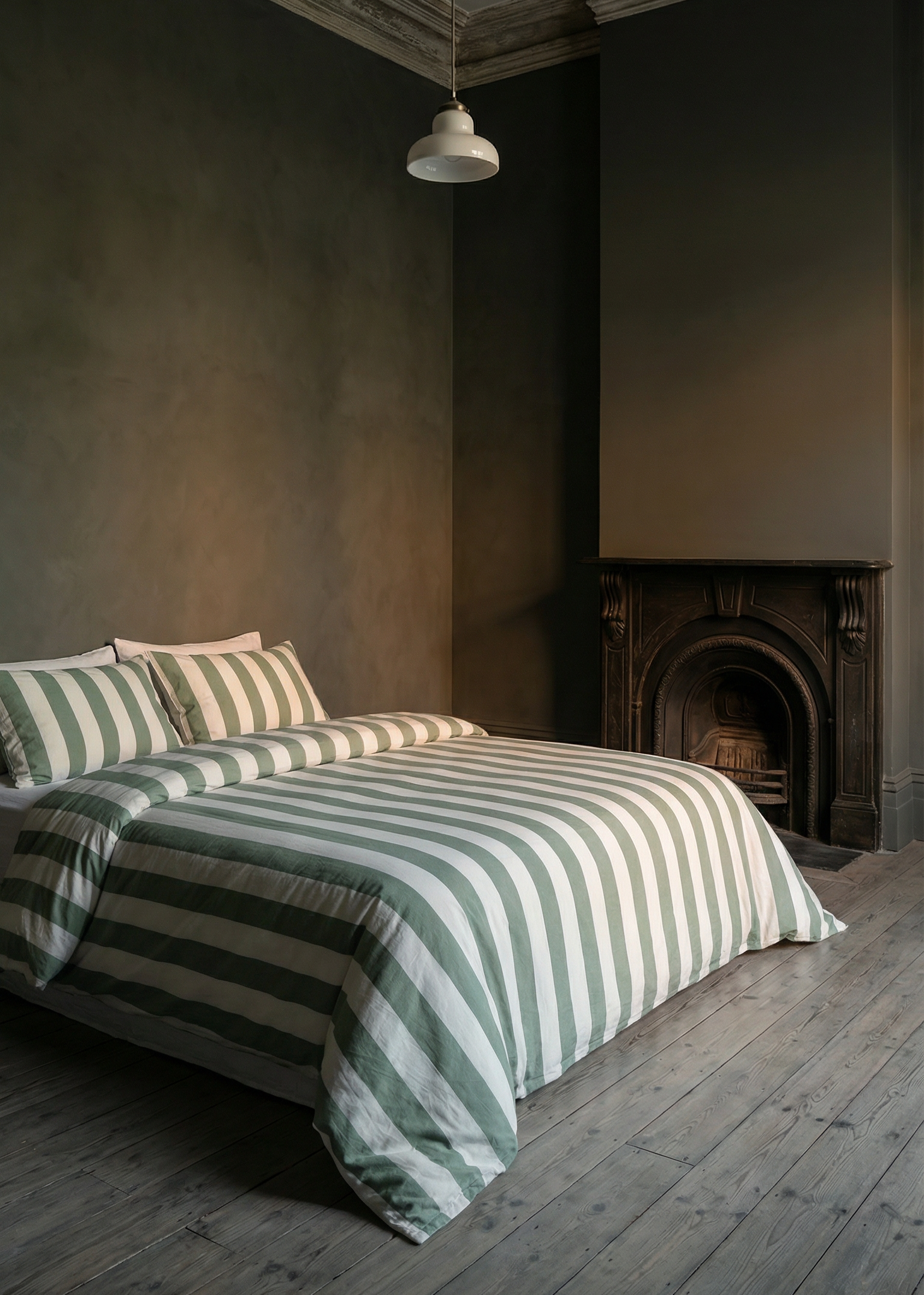 Bedroom with striped bedding and a fireplace in a dimly lit room.