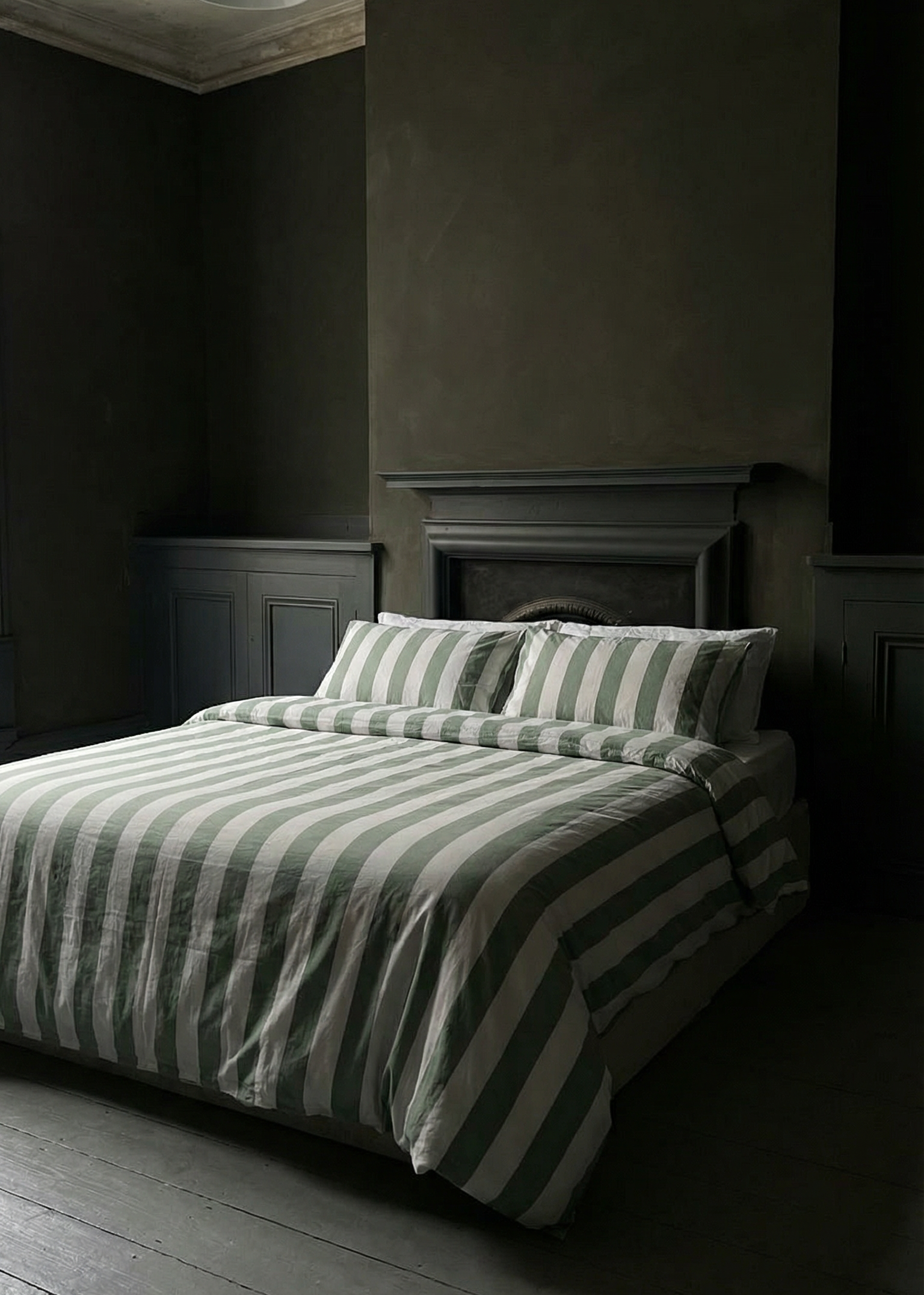 Dark bedroom with striped bedding and wooden floor