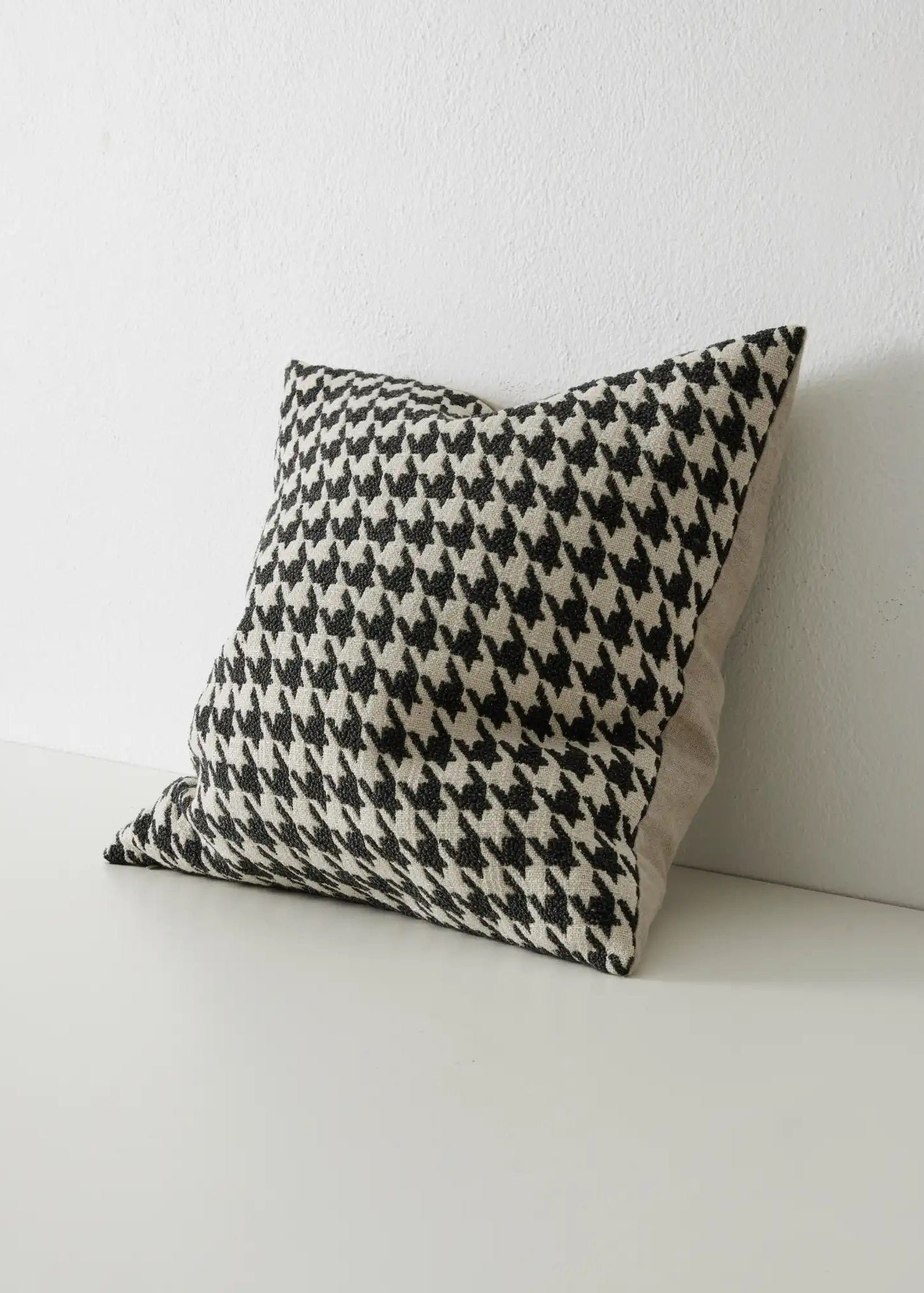 A black and white houndstooth cushion with a boucle texture, displayed against a neutral background.