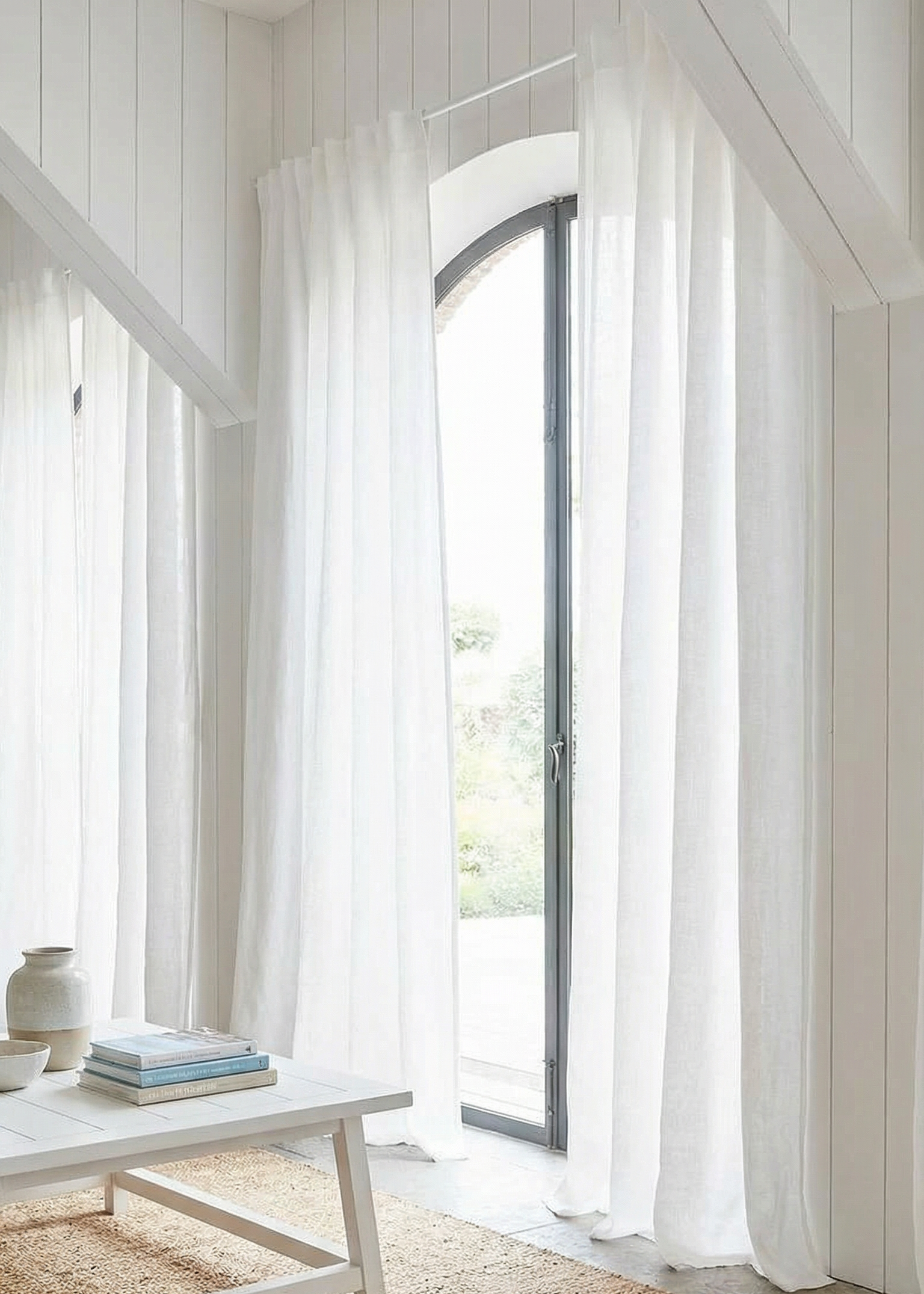 White curtains in a room with a wooden floor and a table.