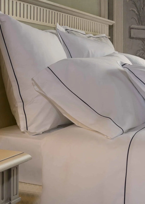 Neatly made bed with white bedding and pillows in a bedroom setting.