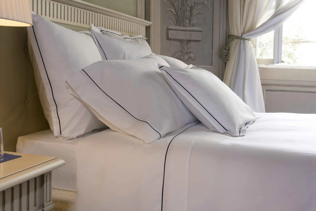 Neatly made bed with white bedding and pillows in a bedroom setting.