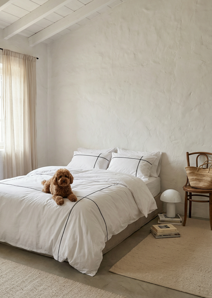 Dog sitting on a bed in a cozy bedroom with neutral tones.