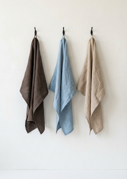 Three towels in brown, blue, and beige hanging on a white wall.