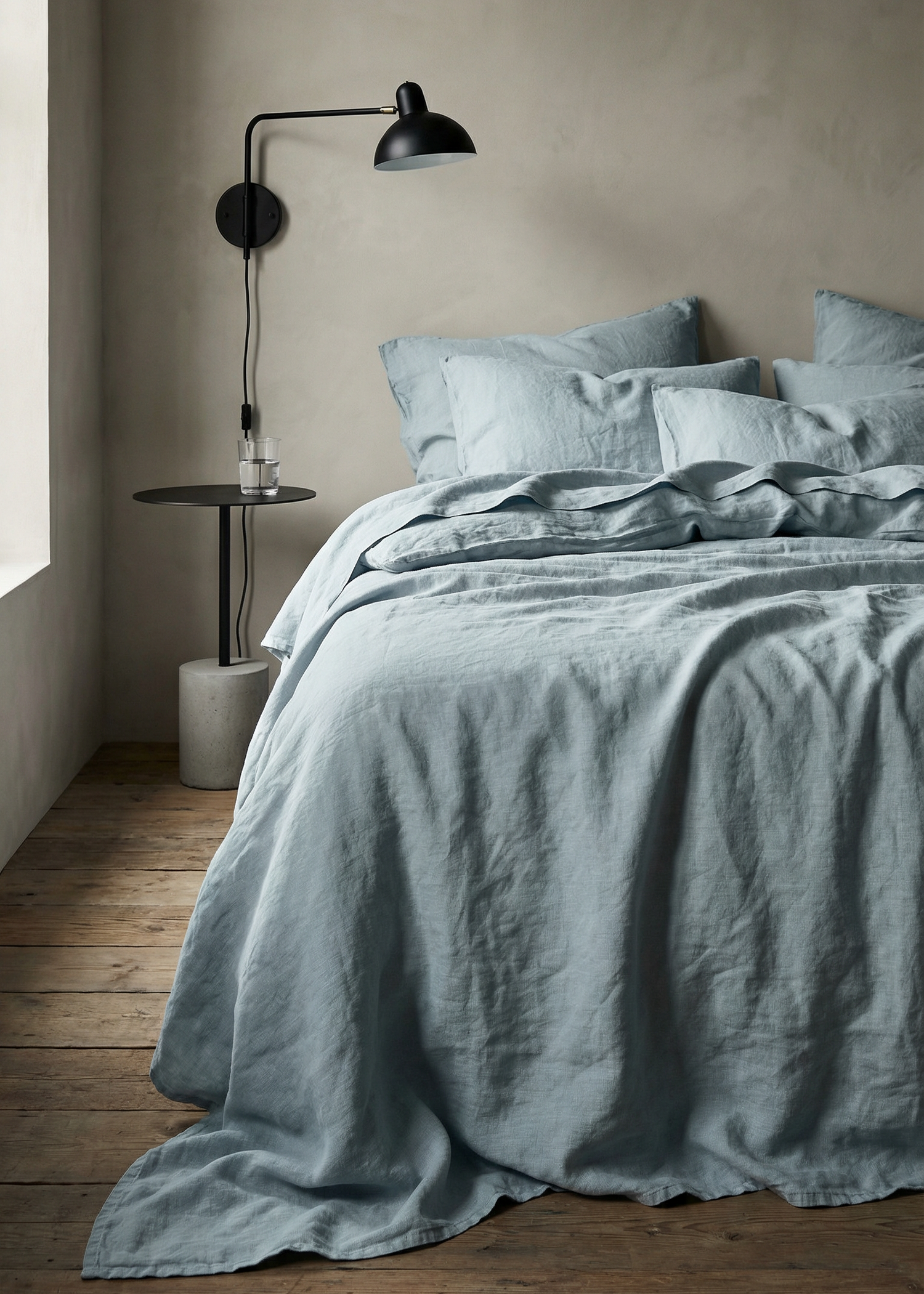 Bedroom with light blue bedding and a lamp on a side table.