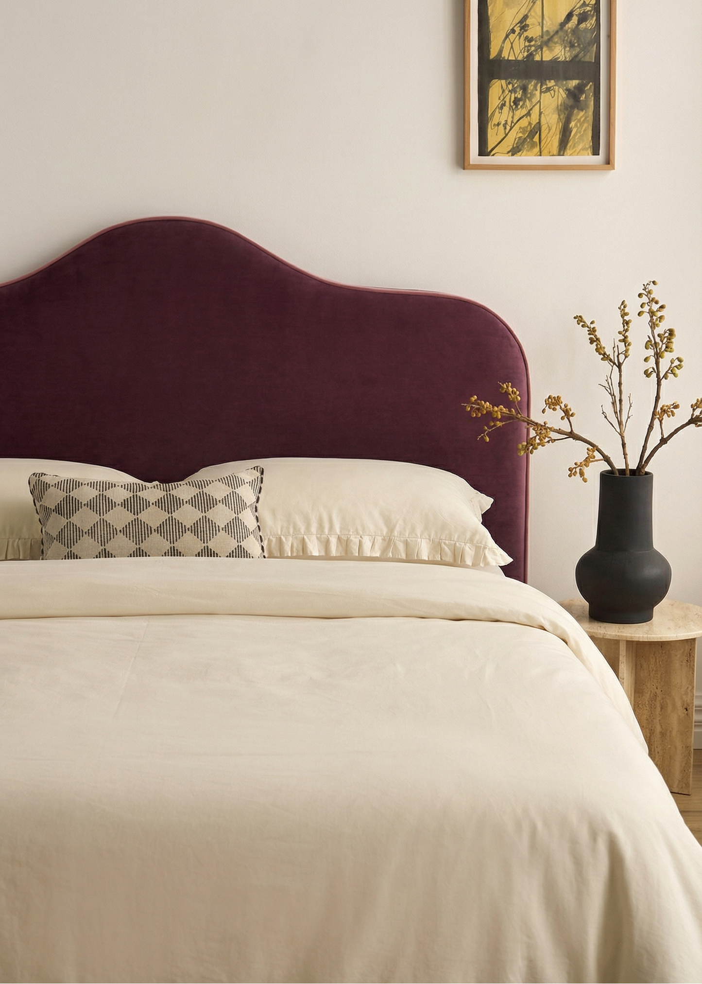 Bedroom with a purple headboard, beige bedding, and a vase with flowers on a nightstand.