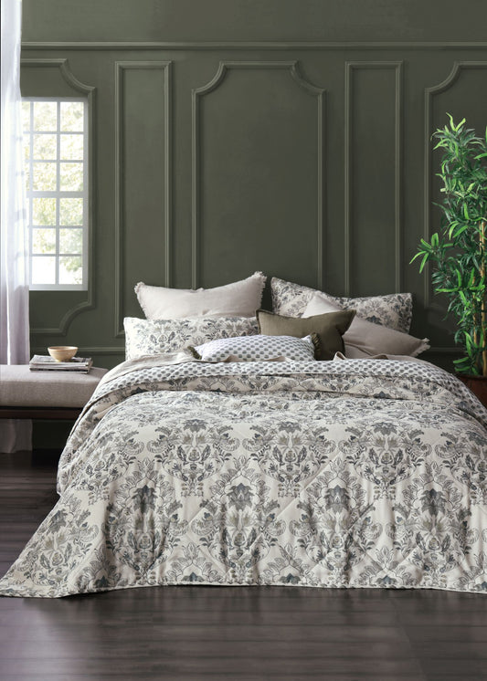 Bed with patterned bedding against a dark green paneled wall.
