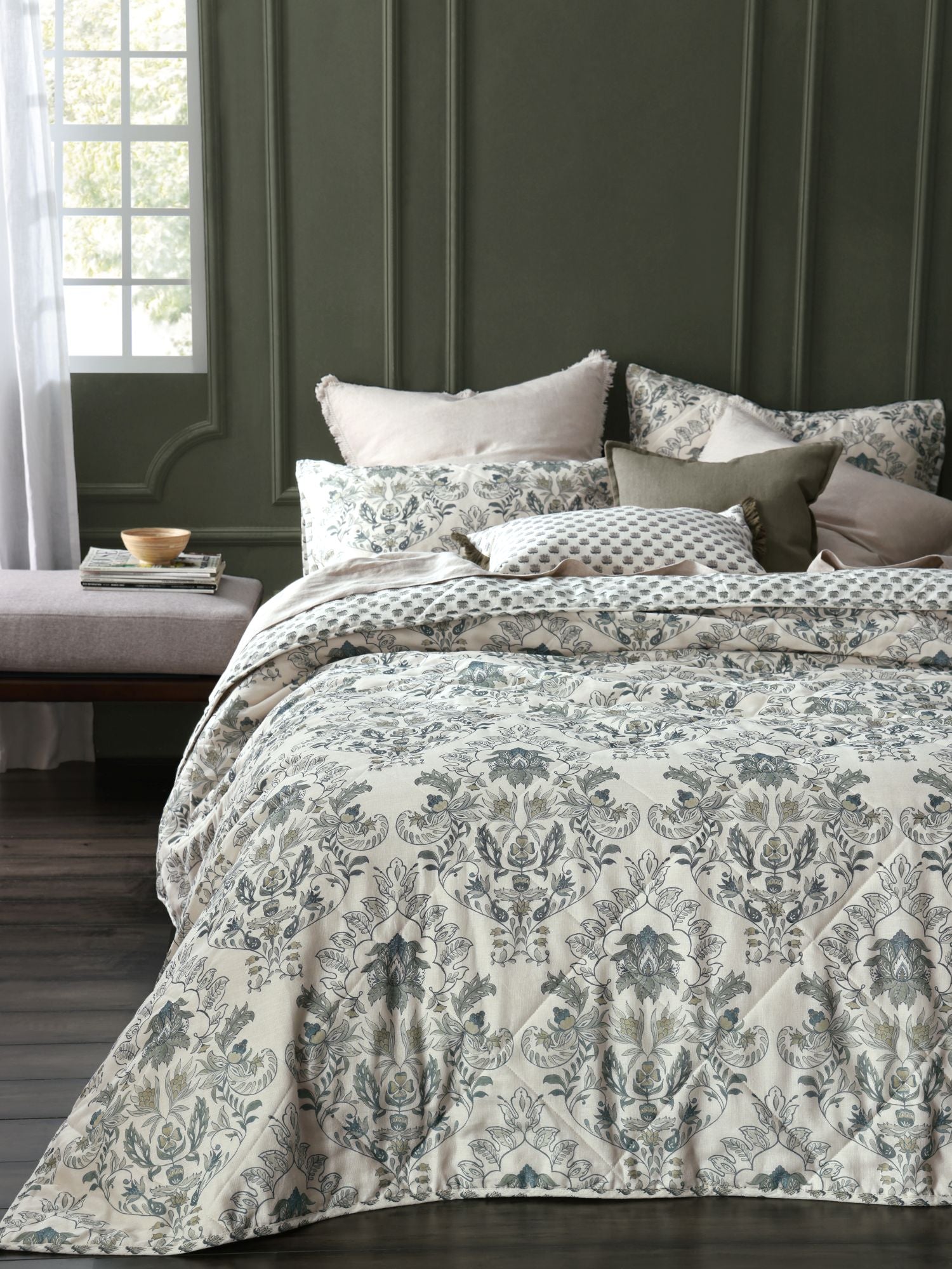 Bed with floral patterned bedding against a dark green wall