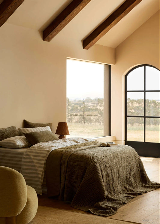 Cozy bedroom with a large bed, lamp, and large windows.