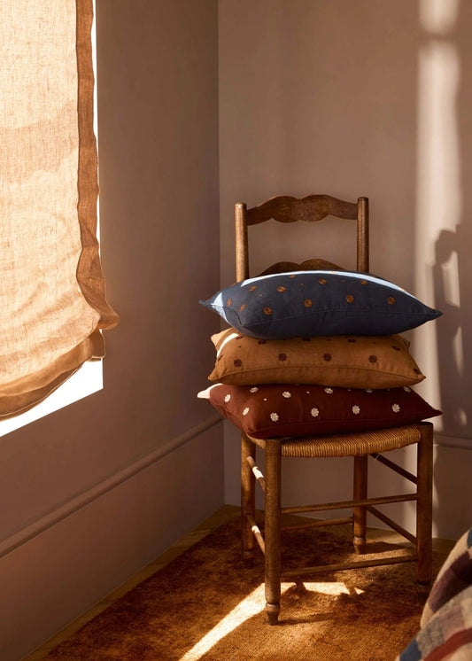 Chair with pillows against a wall with draped curtains
