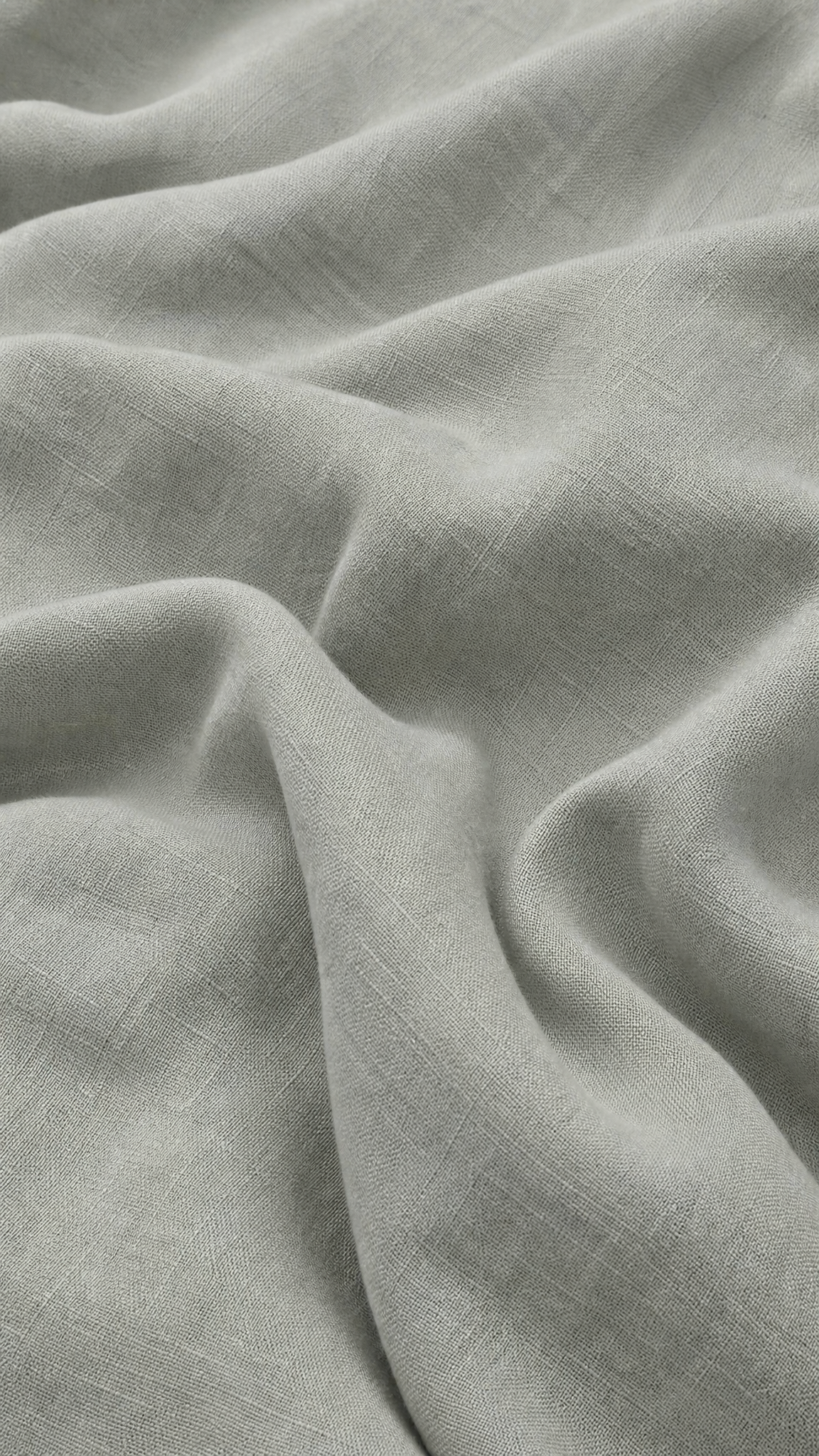 A close-up of draped light gray fabric with a soft, slightly textured weave and gentle folds.