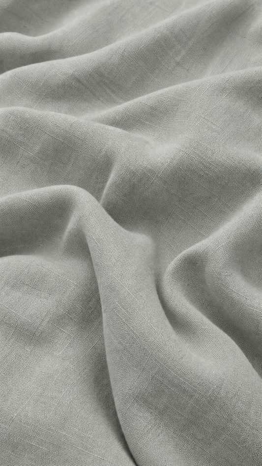 A close-up of draped light gray fabric with a soft, slightly textured weave and gentle folds.
