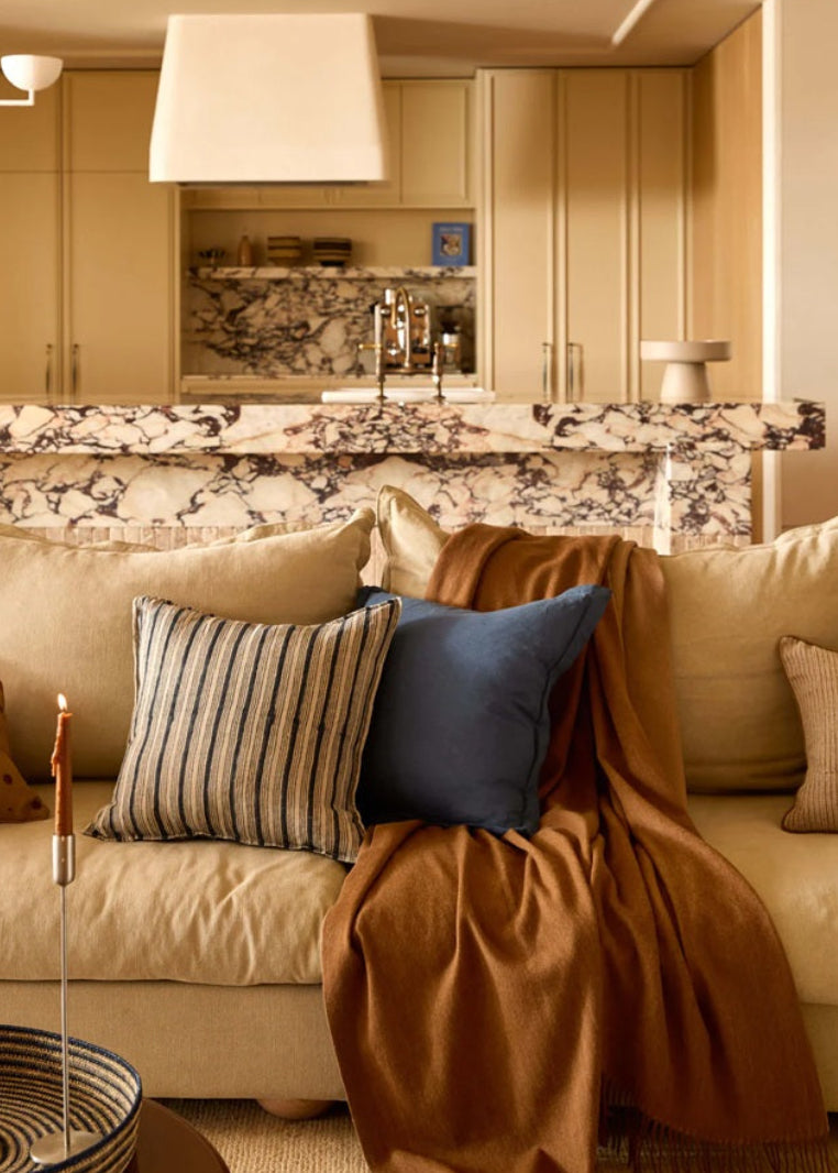 Cozy living room with beige sofa, decorative pillows, and a fireplace.