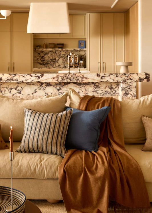 Cozy living room with beige sofa, decorative pillows, and a fireplace.