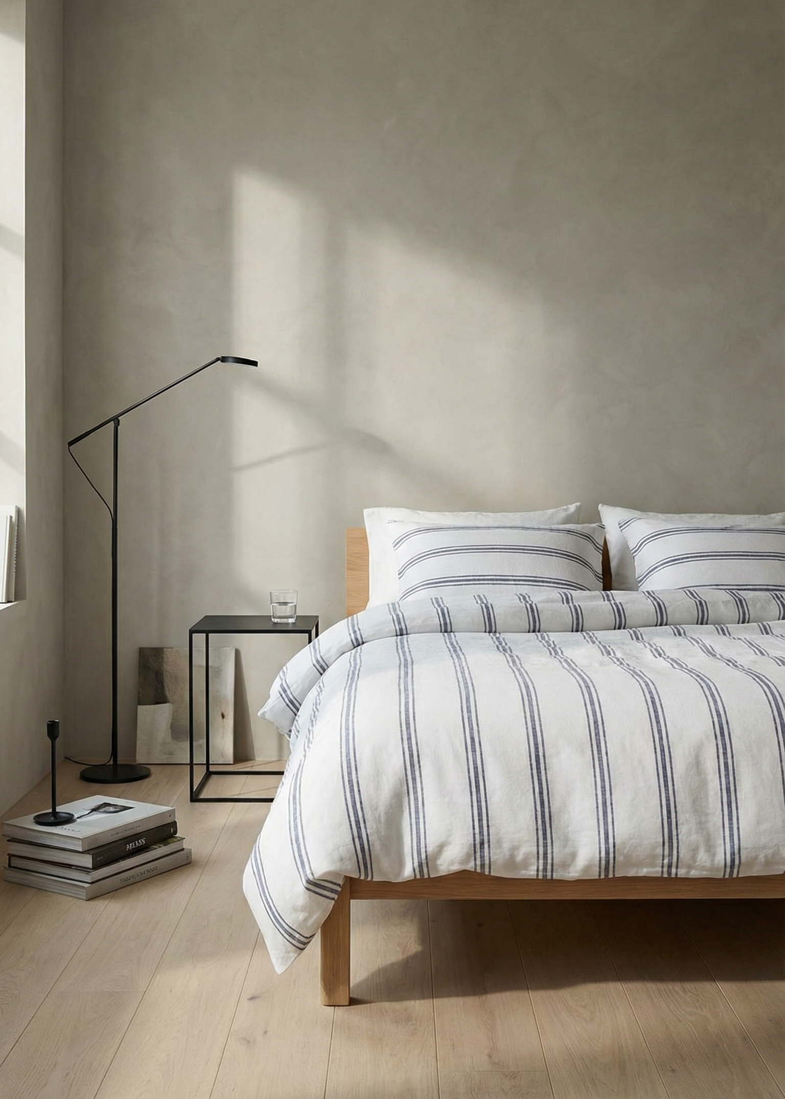 Bedroom with striped bedding and a lamp on a wooden floor.