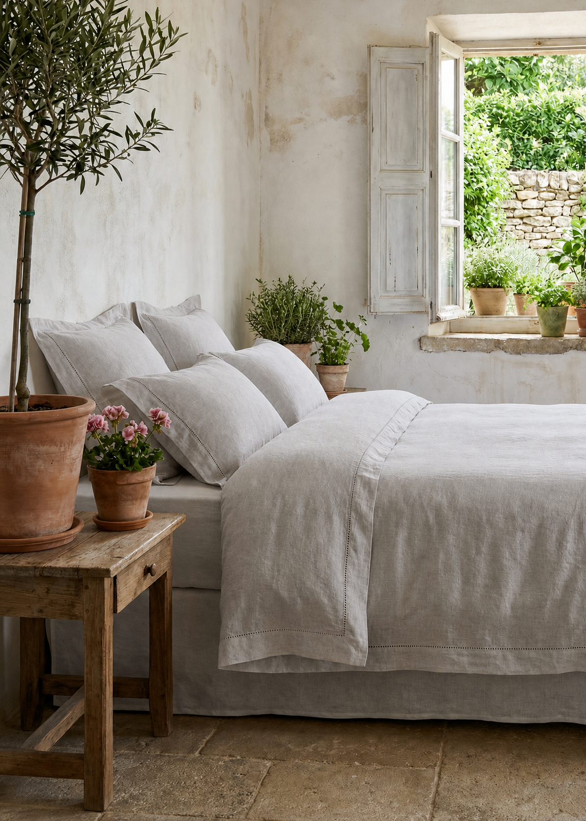Cozy bedroom with a bed, plants, and a window view of greenery.