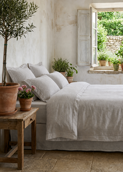 Cozy bedroom with a bed, plants, and a window view of greenery.