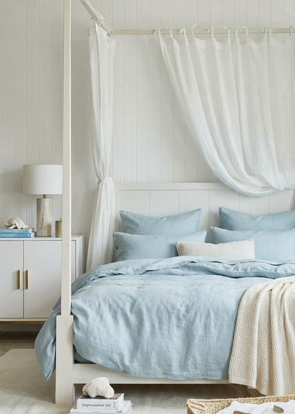 Bedroom with a canopy bed featuring light blue bedding and white curtains.