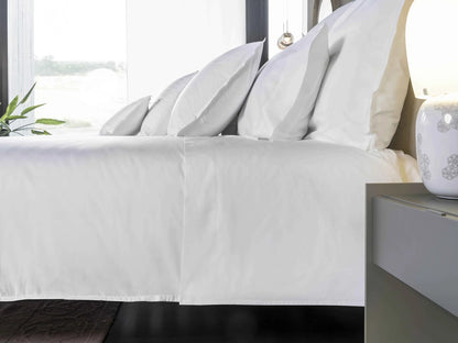 White bed with pillows and a nightstand in a bright bedroom
