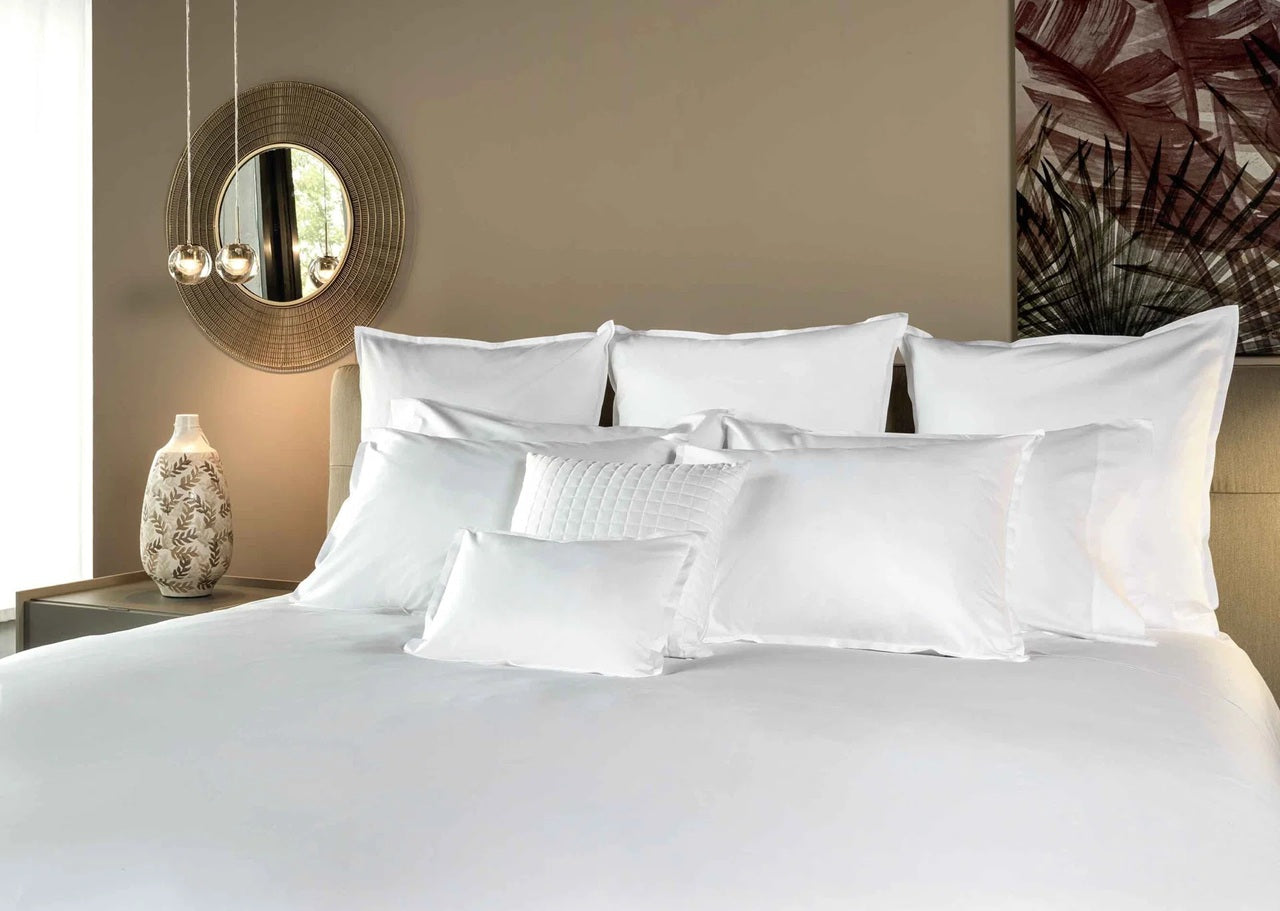 Neatly made bed with white pillows and duvet in a bedroom setting.