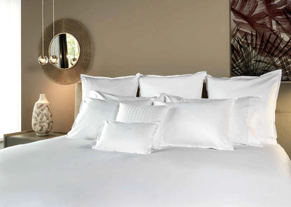 Neatly made bed with white pillows and duvet in a bedroom setting.