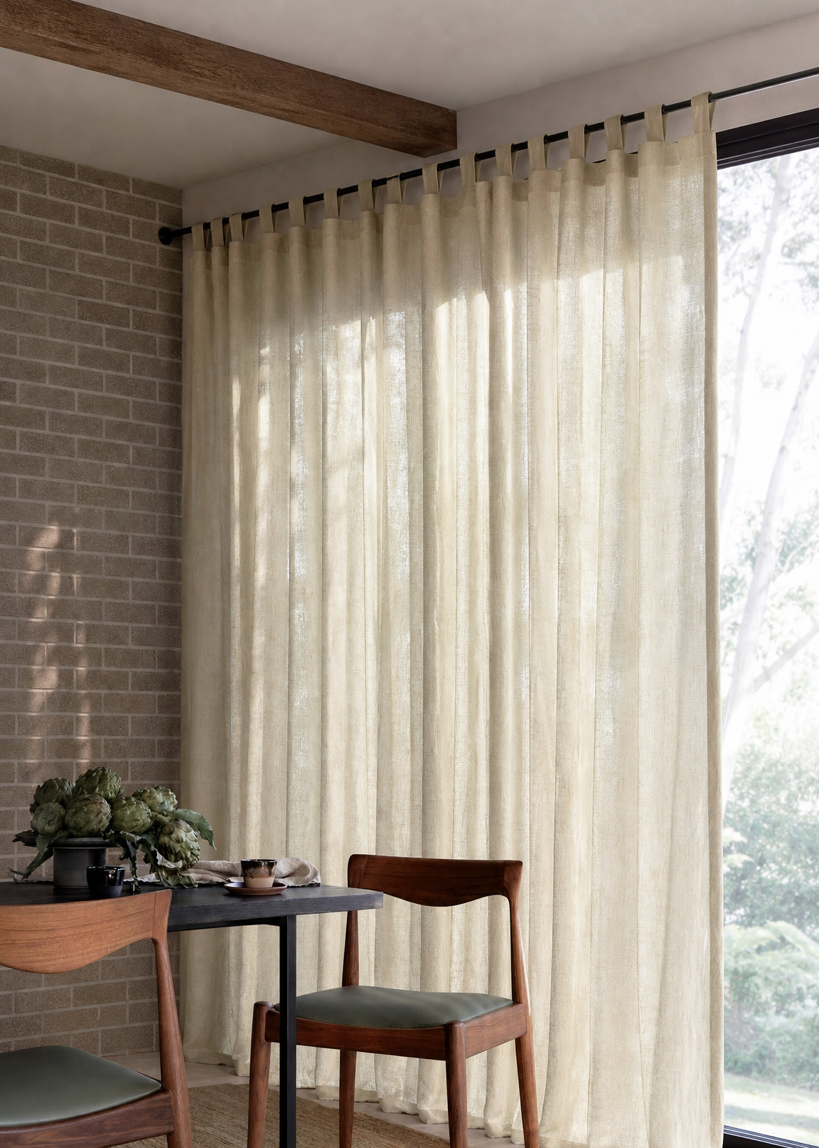 Dining area with wooden chairs and a table near a large window with sheer curtains.