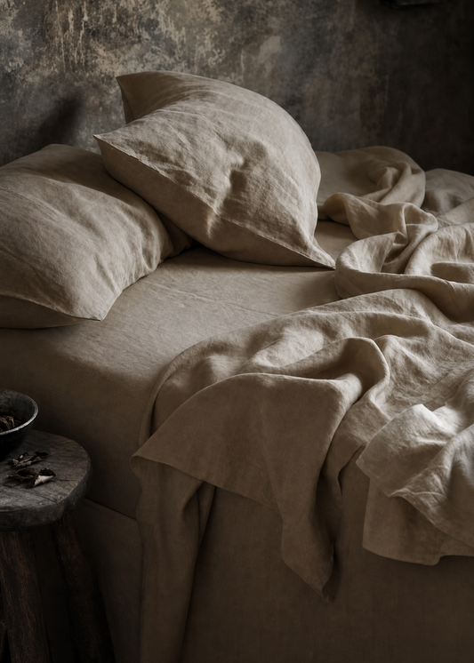 Bed with beige pillows and sheets against a textured wall.