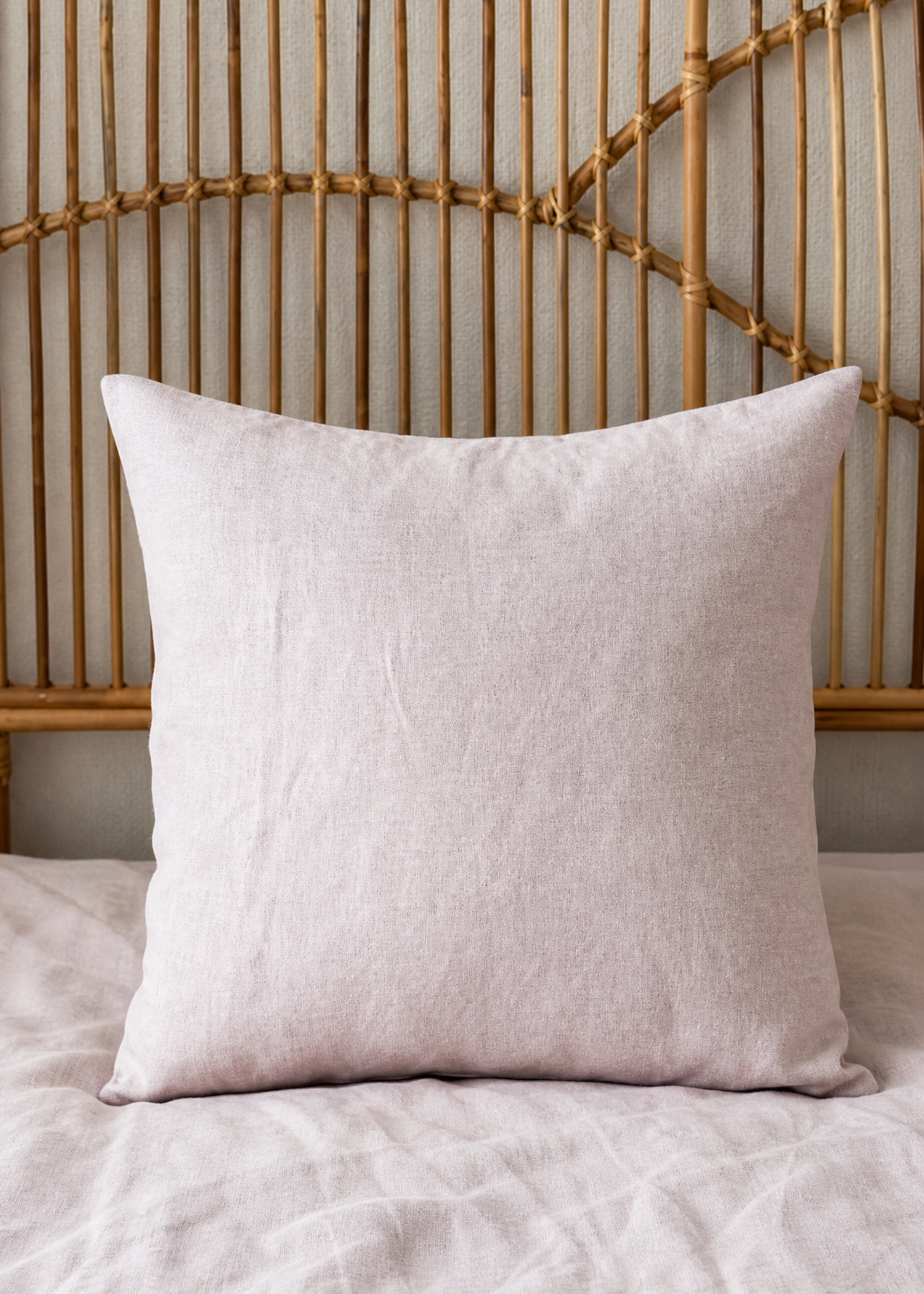 Beige pillow on a bed with a woven headboard