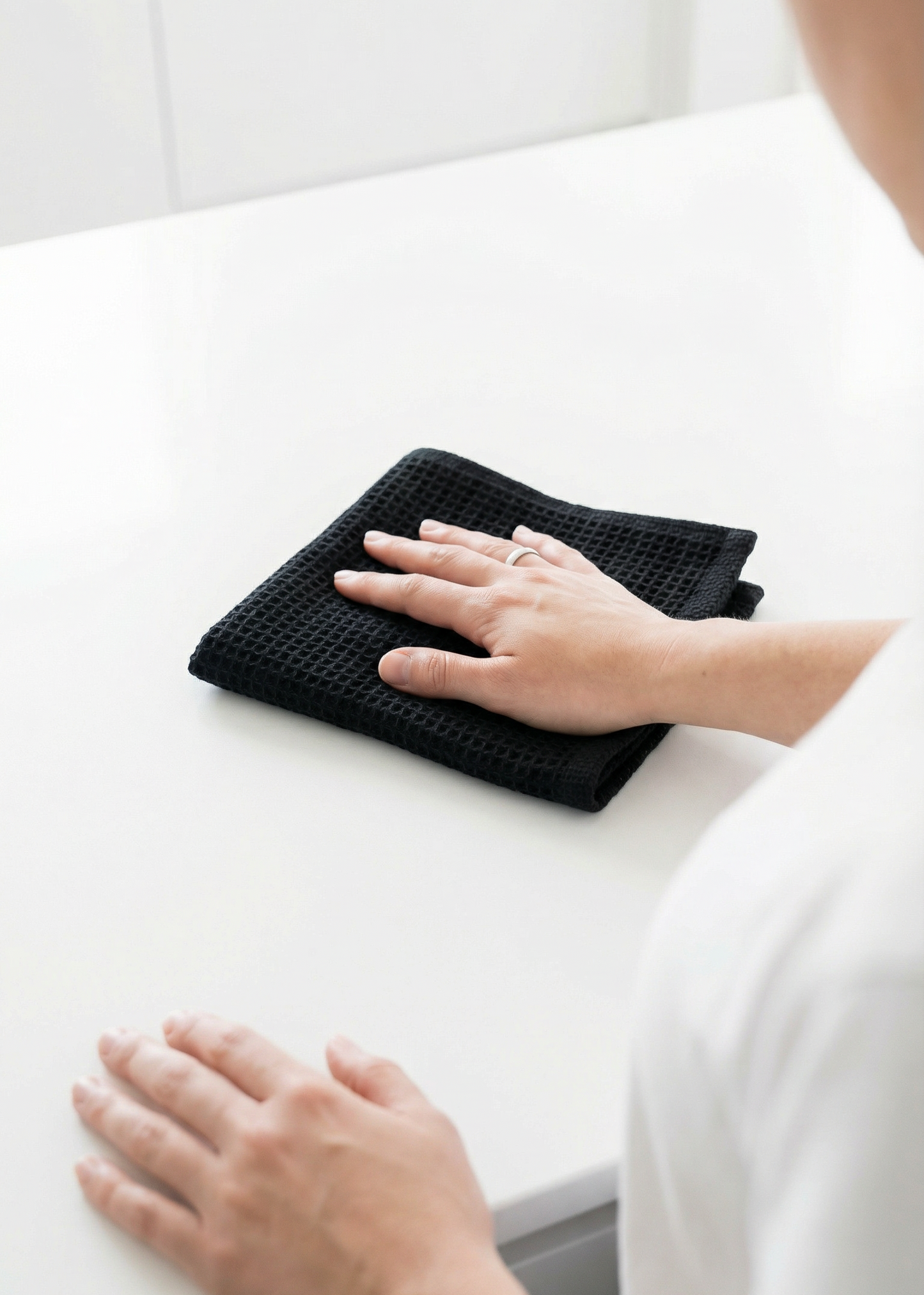 Person cleaning a white countertop with a black cloth