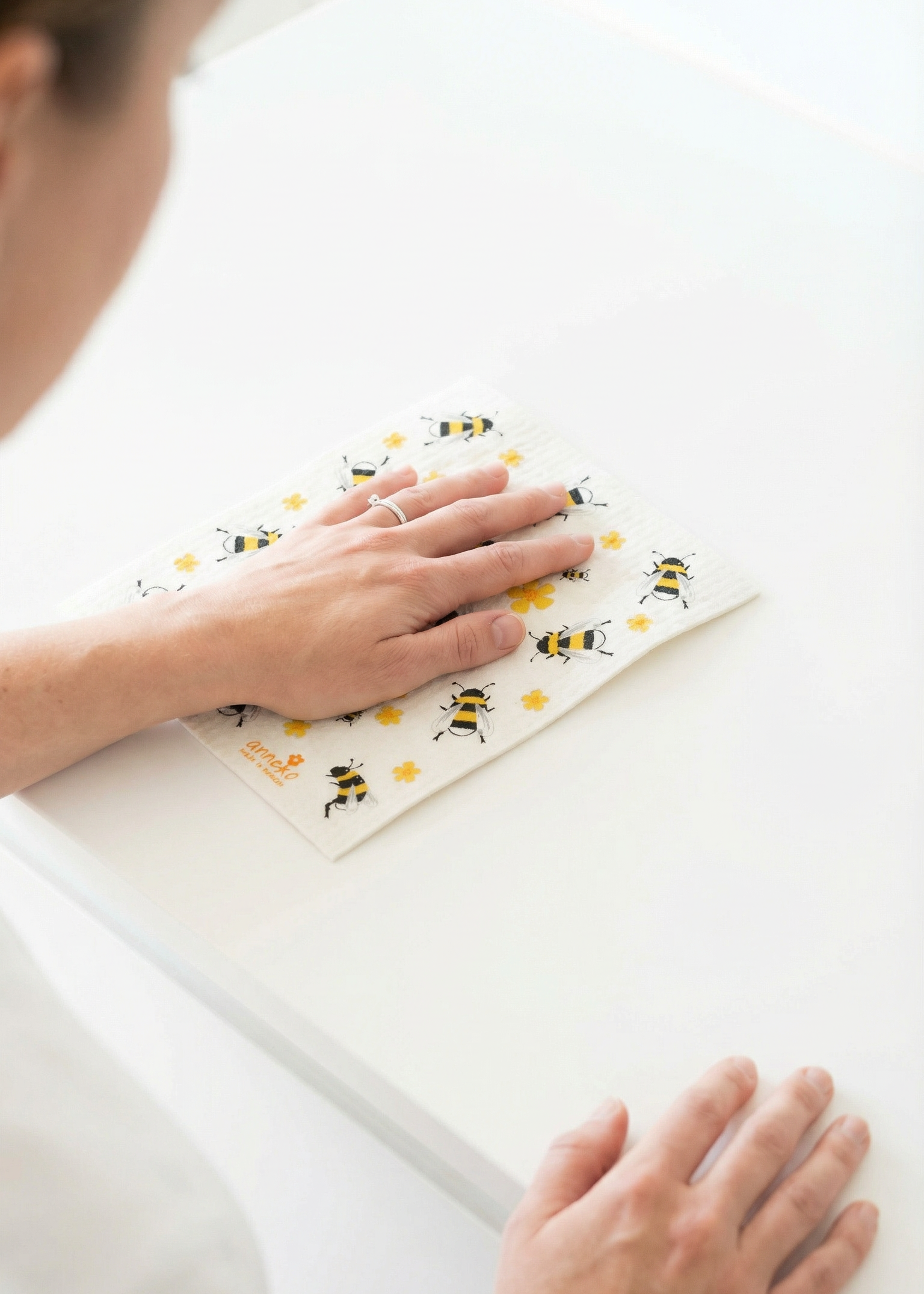 Person applying a decorative sticker with bee designs on a surface.
