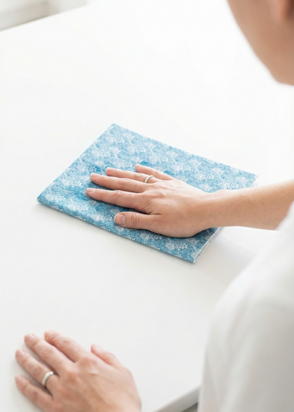 Person cleaning a white surface with a blue microfiber cloth.