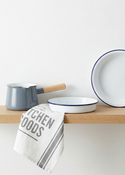Enamelware including bowls and a ladle on a wooden shelf with a kitchen towel.