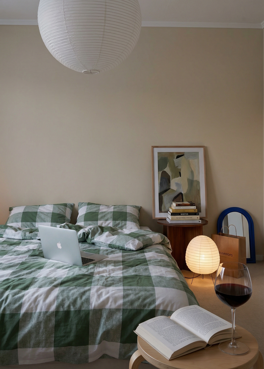 Modern bedroom with a bed, laptop, books, and a glass of wine.
