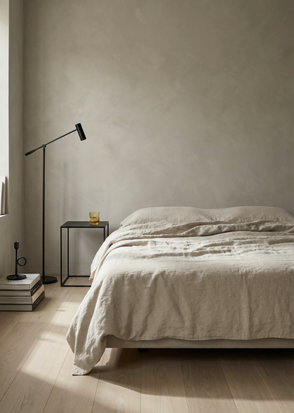 Minimalist bedroom with a bed, side table, and lamp against a plain wall.