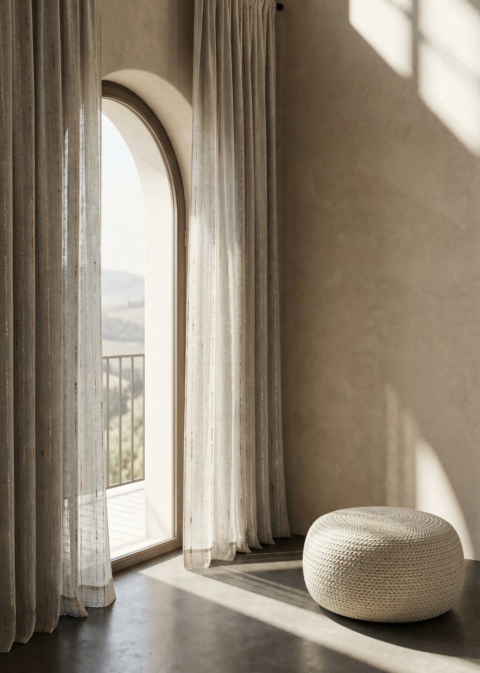 Sheer curtains hanging in a room with a window and a textured wall.