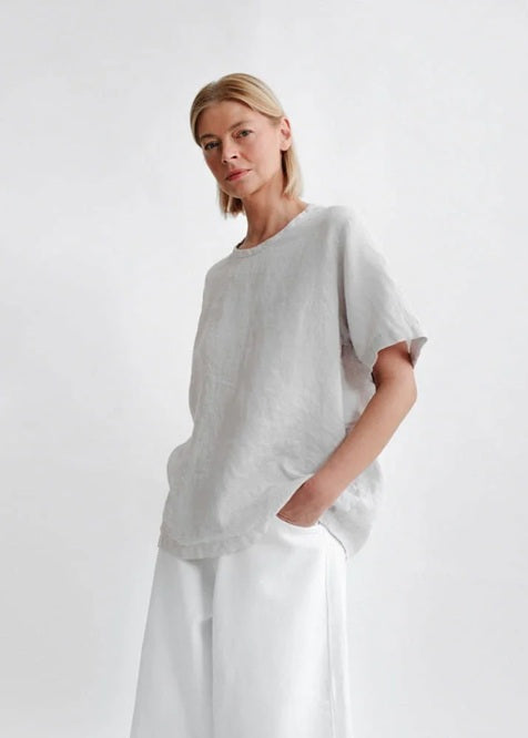 Person wearing a light gray top and white pants on a plain background