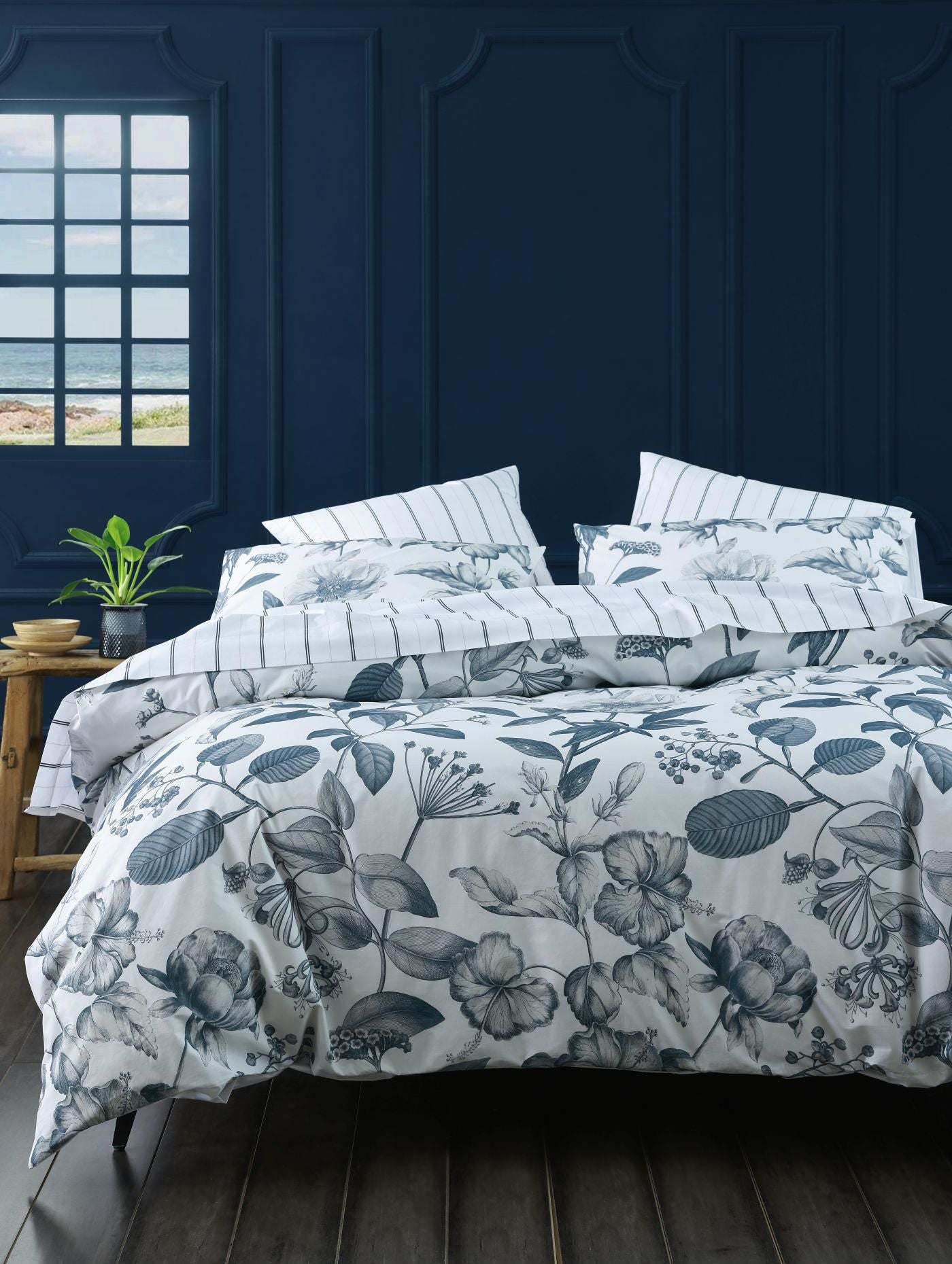 Floral bedding set on a bed with a dark blue wall and window in the background