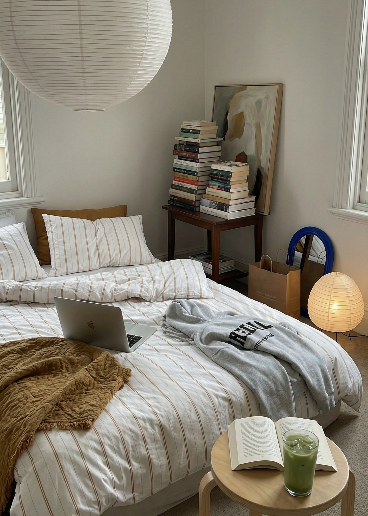 Cozy bedroom with two beds, a laptop, books, and a green drink on a small table.