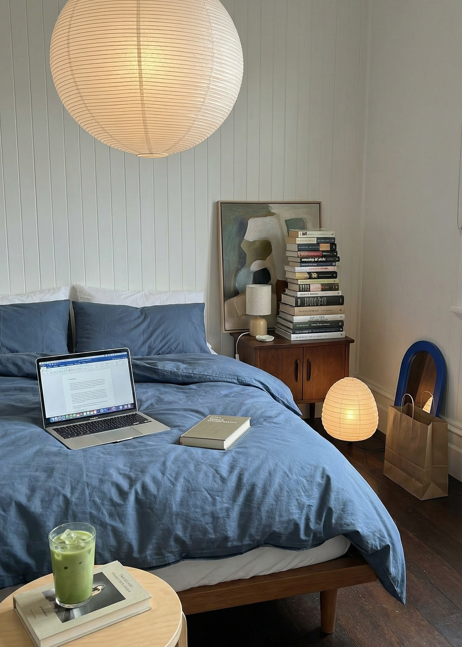 Modern bedroom with blue bedding, laptop, and decor items.