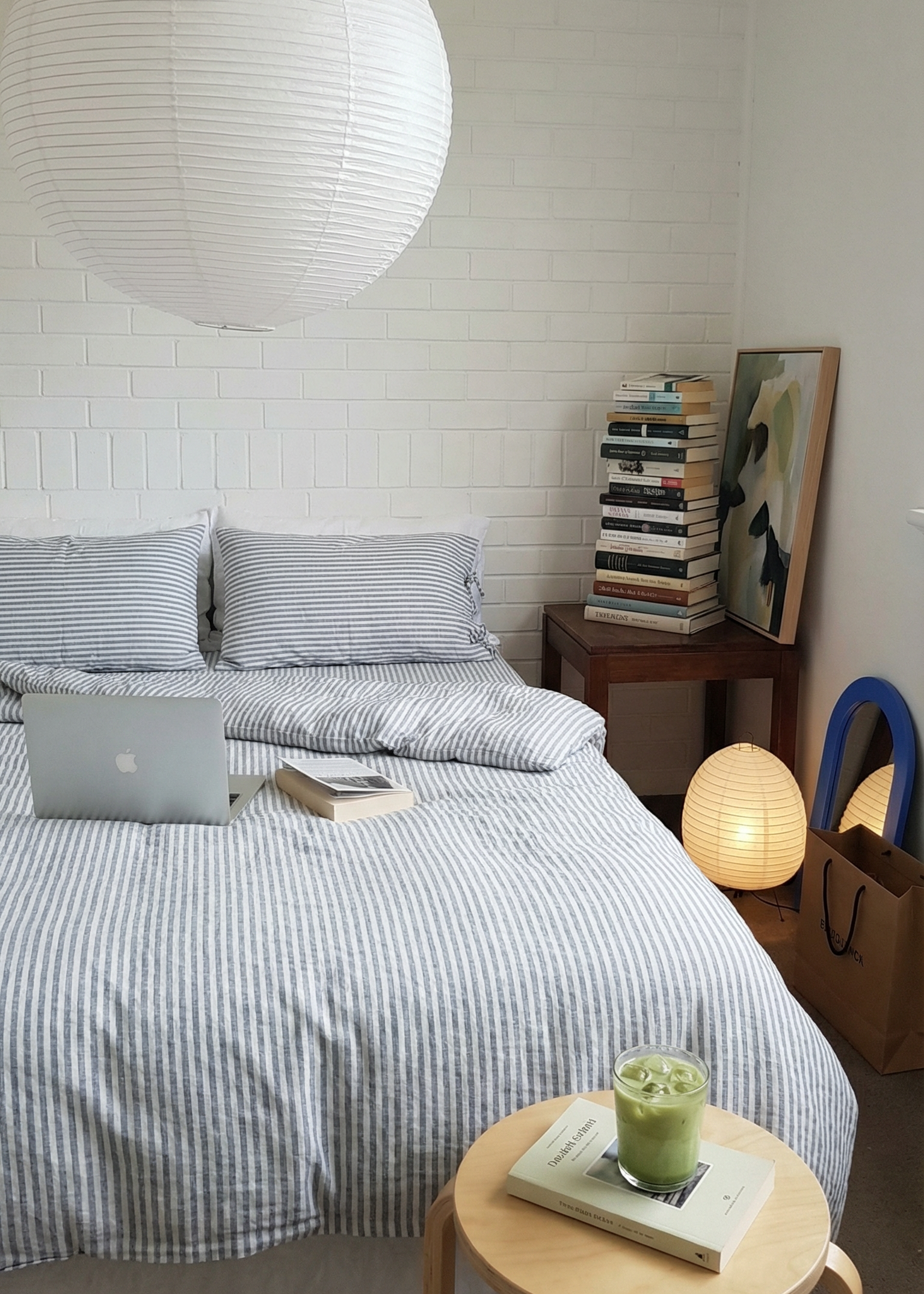 Modern bedroom with striped bedding, laptop, and small round table.