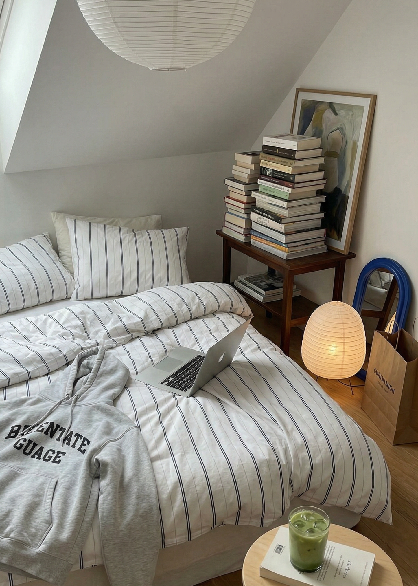 Small bedroom with a bed, books, a laptop, and a lamp.