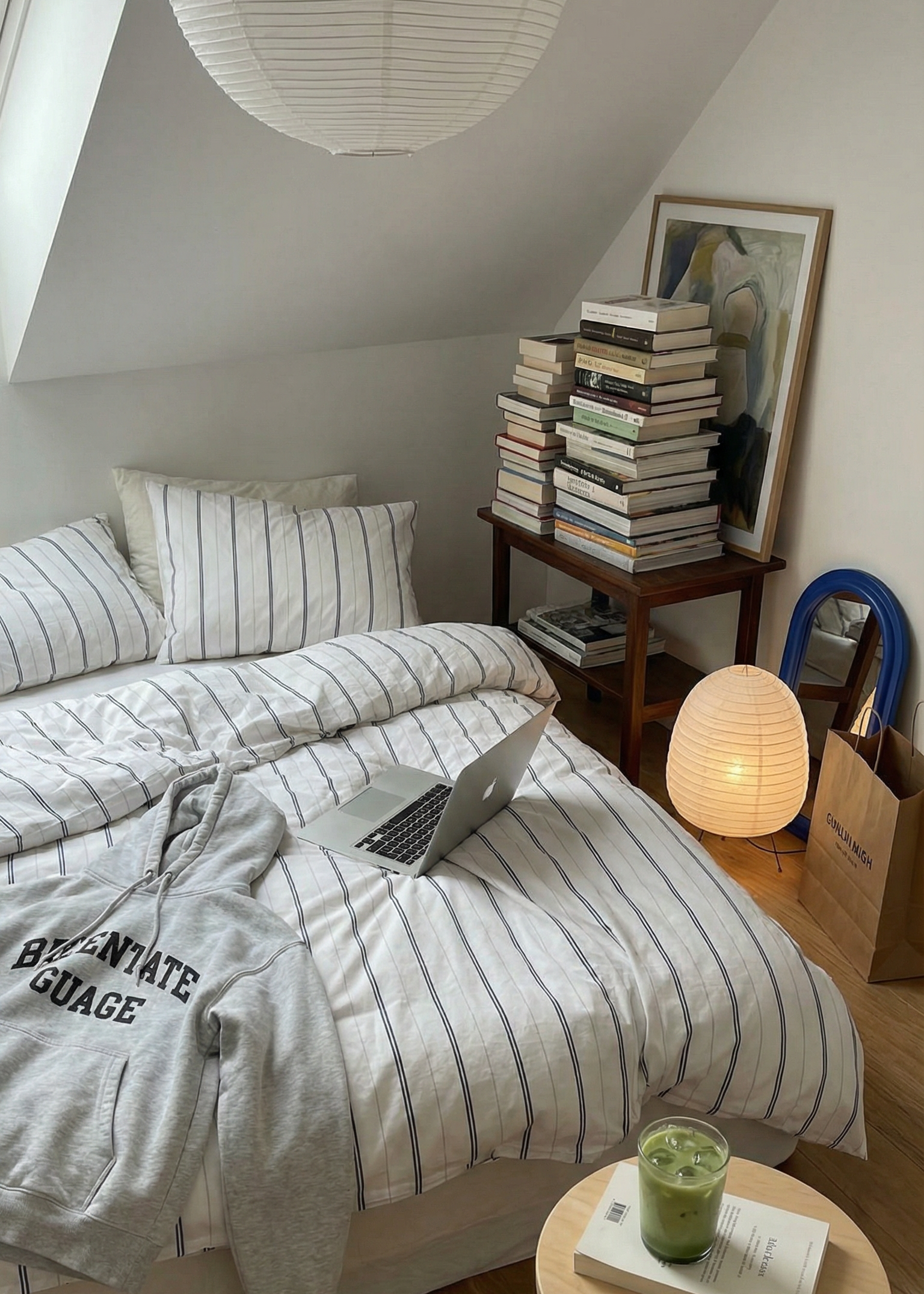 Small bedroom with a bed, books, a laptop, and a lamp.